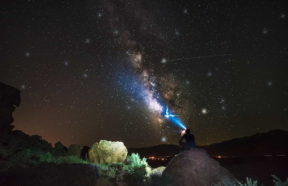 A person stargazing at the night sky while camping in the desert.