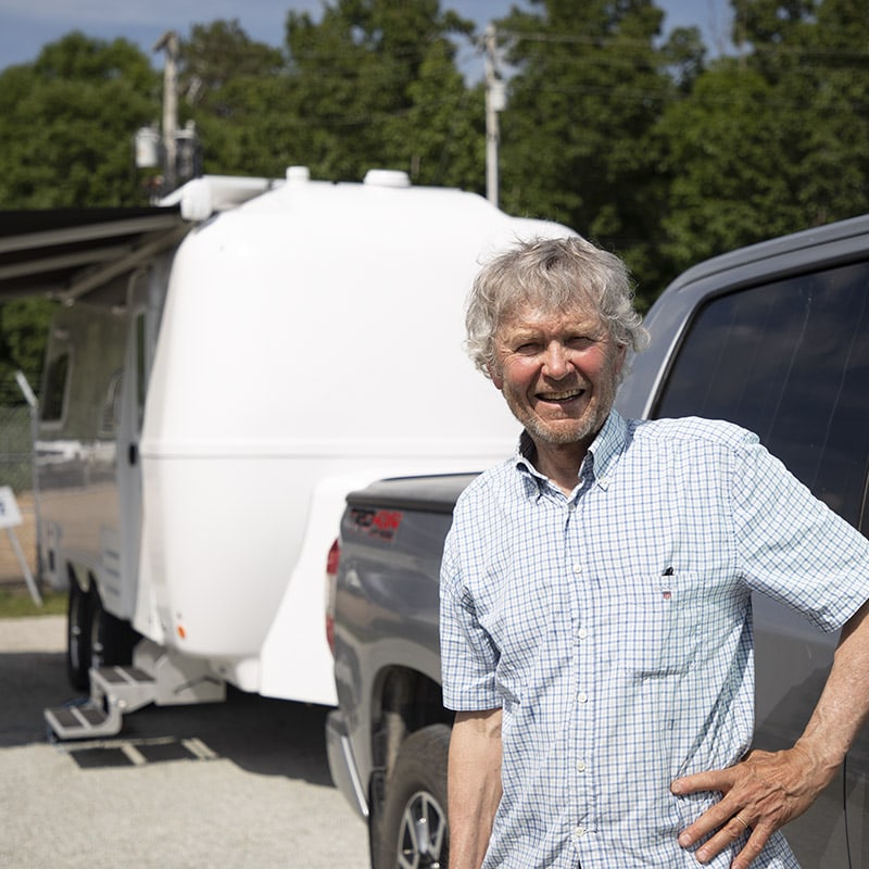 Owner showcasing a spacious and well-equipped travel trailer interior to a potential buyer