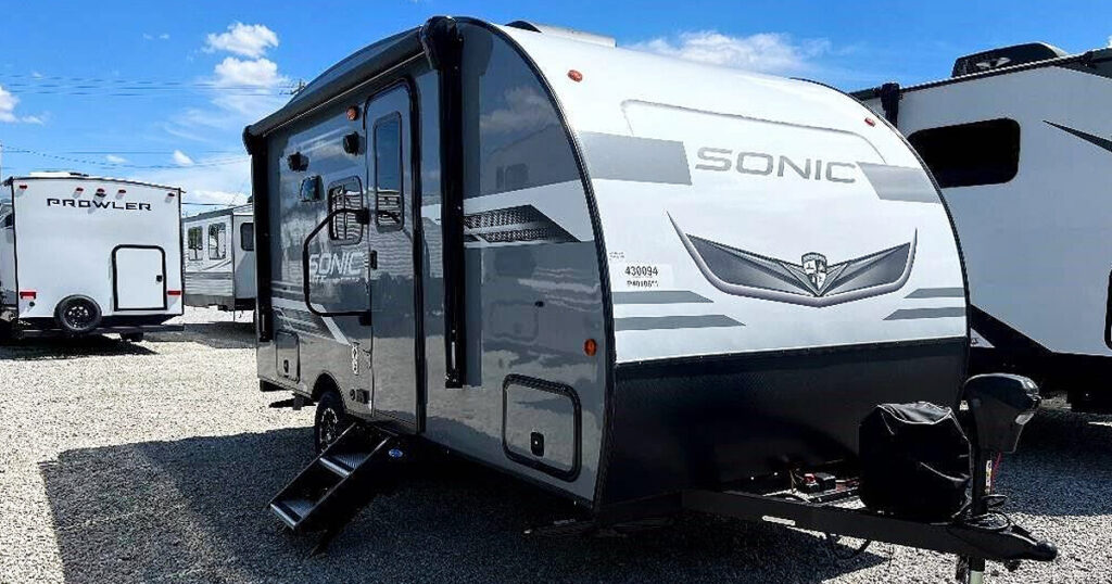 The slide-outs are extended, creating extra living space inside. The RV is equipped with awnings and outdoor furniture, inviting relaxation and outdoor activities.