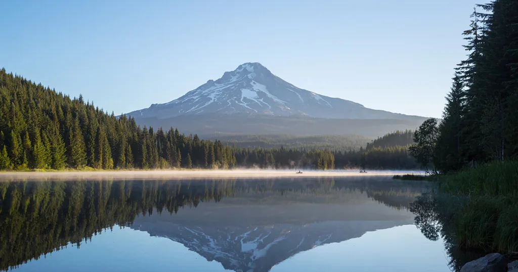 A breathtaking view of Mount Hood, Oregon, showcasing its majestic snow-capped peak, surrounded by lush green forests.