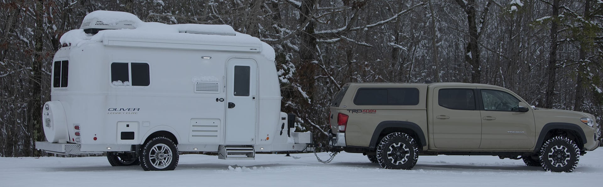 A well-maintained, compact and versatile four-season travel trailer parked in a picturesque camping spot.