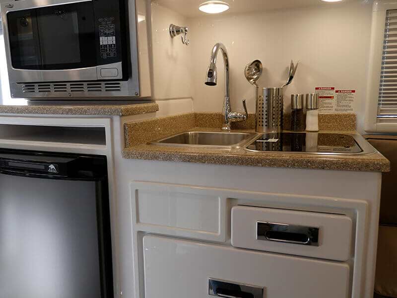 The camper trailer inside kitchen features a compact and functional space with a sink, stove, and countertop.