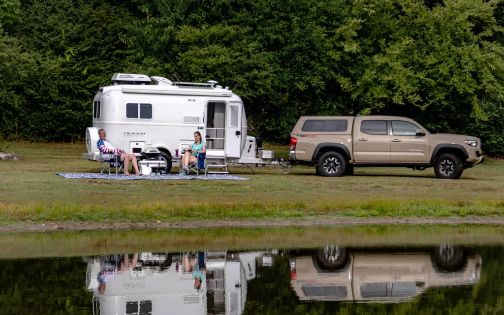 A couple camping next to the lake with their small trailer rv