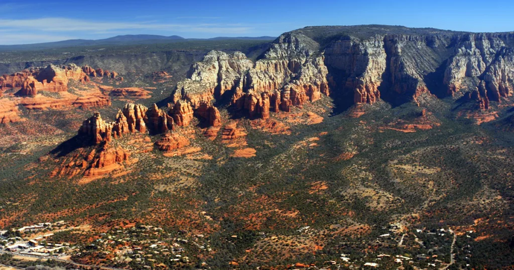 Sedona's famous red rock formations, Cathedral Rock, Bell Rock, and Courthouse Butte, against a blue sky, showcase the breathtaking beauty and spiritual energy of this popular destination for outdoor activities, art galleries, and wellness retreats in northern Arizona.