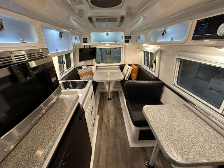 Inside view of a compact camper, and is yet surprisingly roomy, the Oliver Legacy Elite is packed with premium features such as fiber granite countertops and flooring, plush dinette cushions, energy-efficient LED lighting, and state-of-the-art LED TV with custom speakers and AM/FM/Bluetooth®.