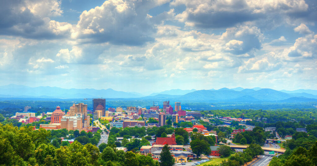 Asheville, North Carolina: A bustling city street lined with colorful shops and galleries, with the Blue Ridge Mountains rising in the distance.