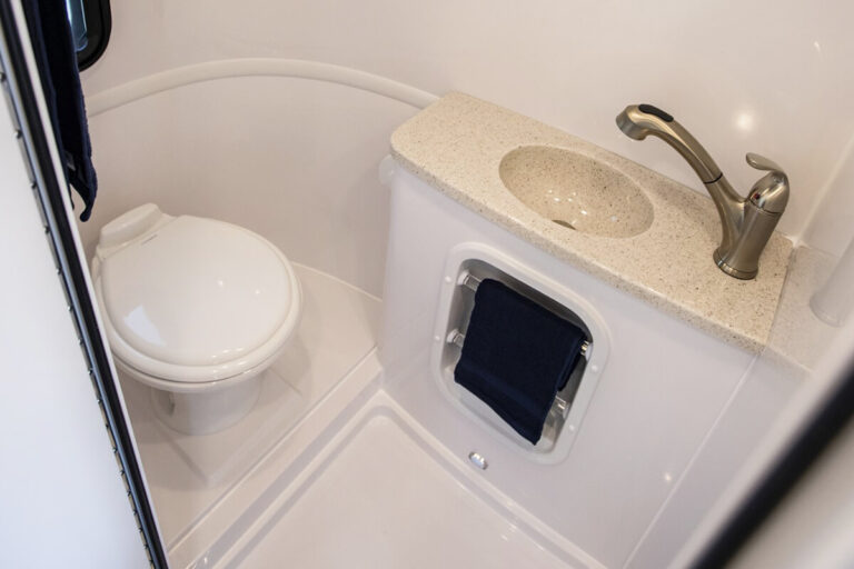 Compact bathroom inside the Legacy Elite small camper with a toilet and shower wand.