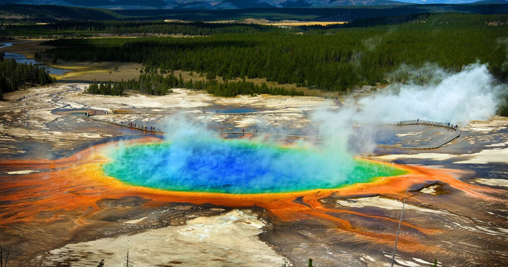 Grand Prismatic Spring — Vibrant rainbow-colored Grand Prismatic Spring with bright blue center, surrounded by orange bacterial mats and boardwalk in Yellowstone National Park.
